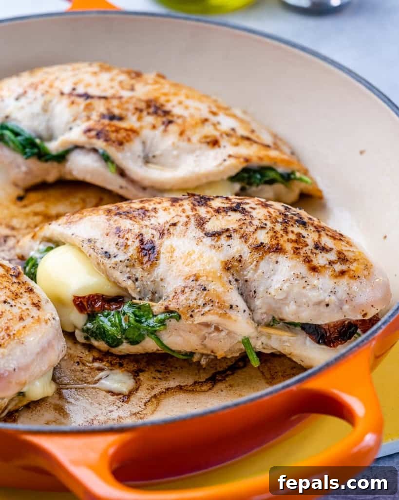 Tuscan Countryside Stuffed Chicken 9 Side view of a skillet filled with Tuscan stuffed chicken, showcasing the creamy sauce and the beautiful golden-brown chicken.