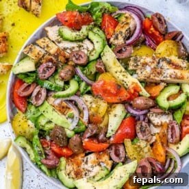 Vibrant Mediterranean Chicken Salad 11 salad in a round bowl bowl with sliced chicken and fresh veggies.