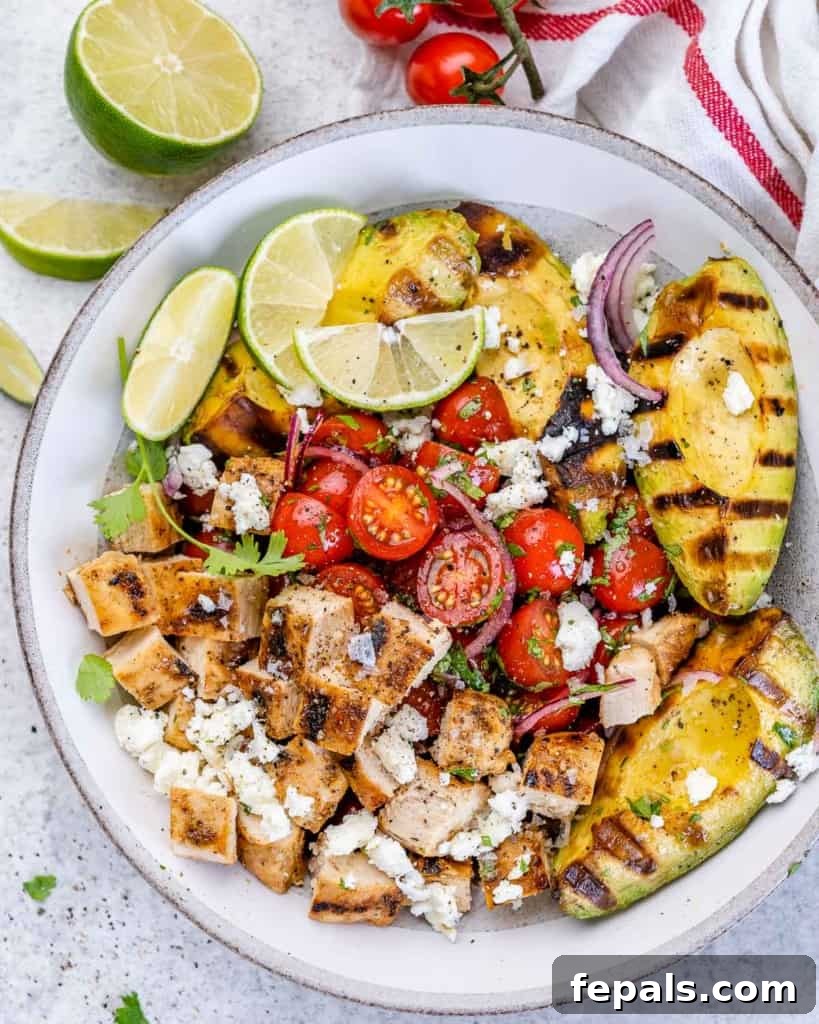 Top view of grilled chicken and avocado salad with fresh limes and red onion