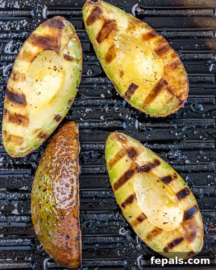 Close-up of perfectly grilled avocado on a hot grill, showing distinct char marks.