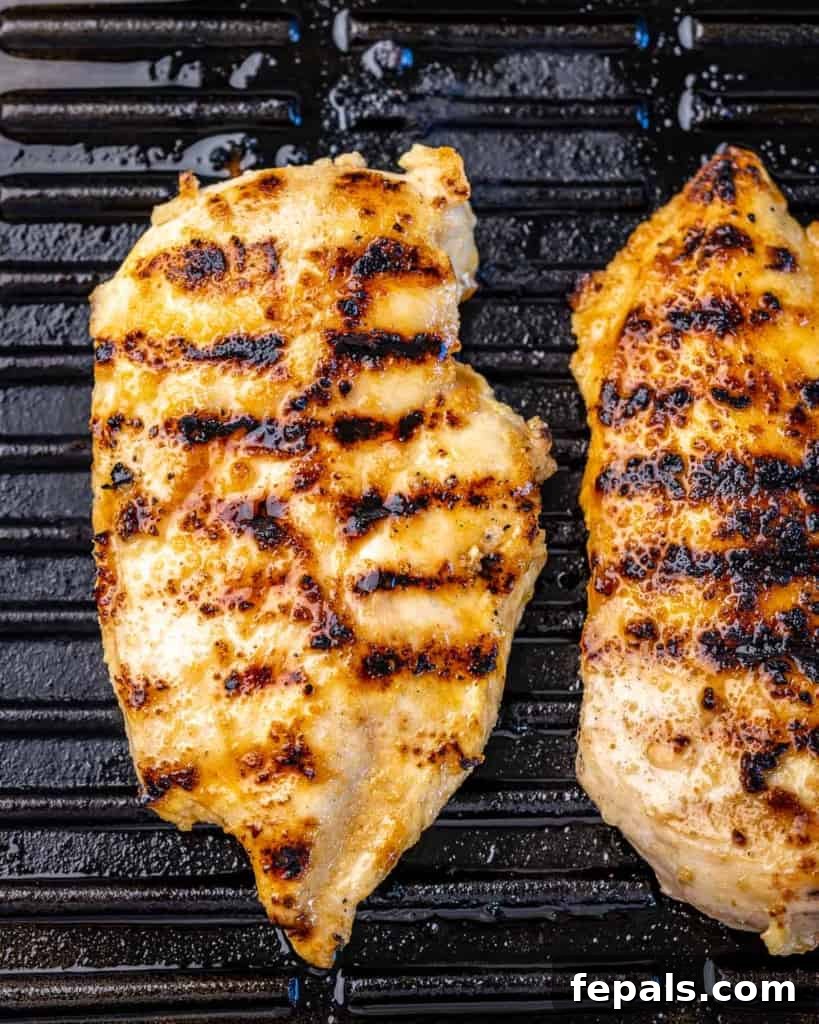 Delicious grilled chicken breasts sizzling on the grill, ready to be added to the salad.