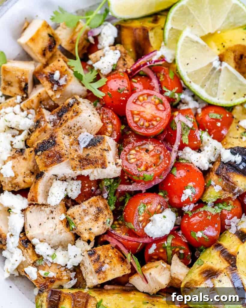 Close-up image of fresh cherry tomatoes nestled within a healthy grilled chicken salad.