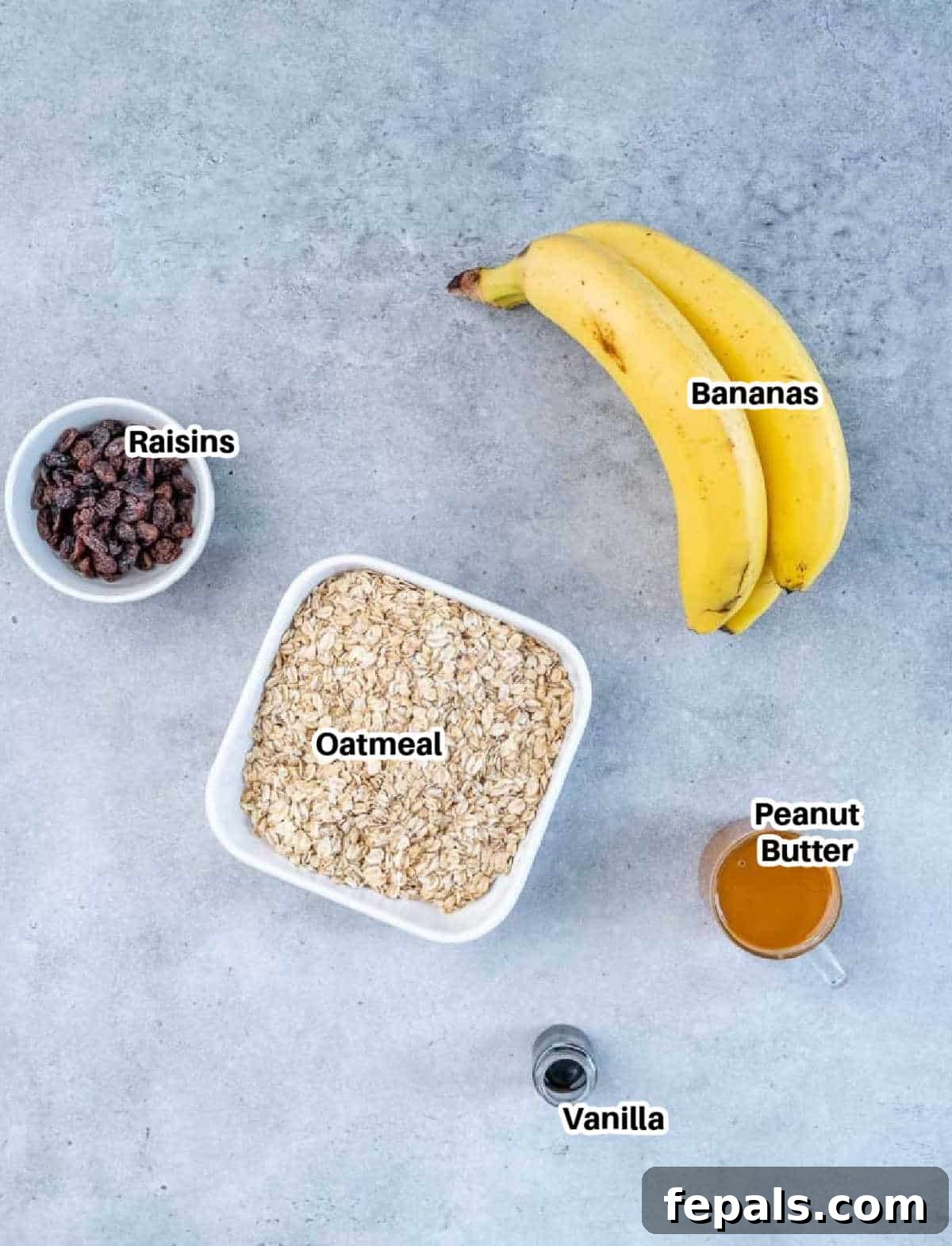 ingredients to make raisin cookies, including bananas, peanut butter, vanilla, oats, and raisins.