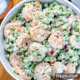 Top view of a creamy shrimp salad with peas and celery in a white bowl, ready to be served.