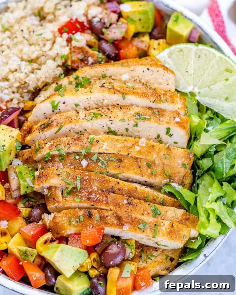 close up chicken taco bowl with sliced chicken breast over lettuce, quinoa, and black bean corn salsa