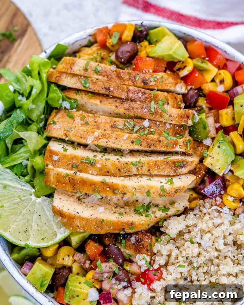 side shot of sliced chicken breast in a white bowl of quinoa and salsa.