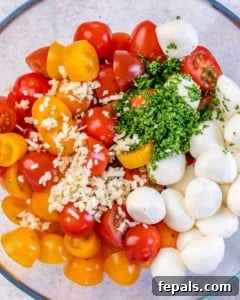 chopped tomatoes, cheese balls, and herbs in a bowl