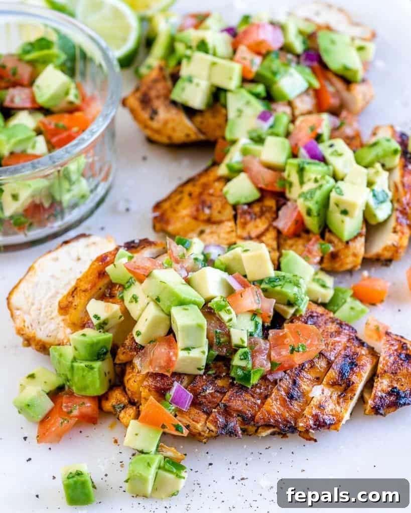 Smoky Grilled Chicken with Zesty Avocado Salsa 2 Side shot of perfectly sliced grilled chicken breasts generously topped with a vibrant green avocado salsa, illustrating a refreshing and healthy meal.