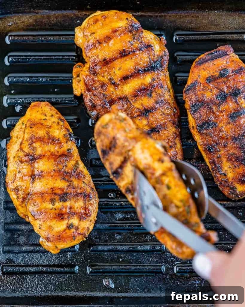 Smoky Grilled Chicken with Zesty Avocado Salsa 6 Chicken breast cooking on a hot grill pan, showcasing the delicious grill marks and sizzling process.