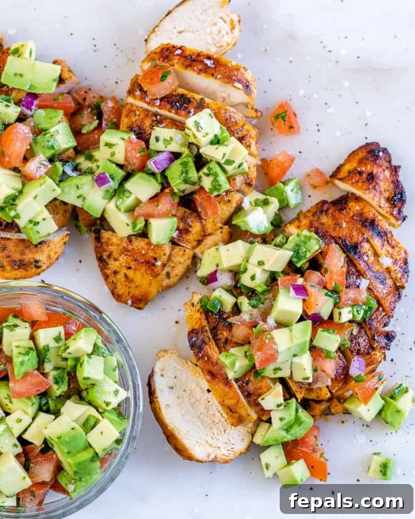 Smoky Grilled Chicken with Zesty Avocado Salsa 8 Top view of a beautifully garnished serving of grilled chicken breast, sliced and adorned with fresh avocado salsa, ready to be enjoyed.