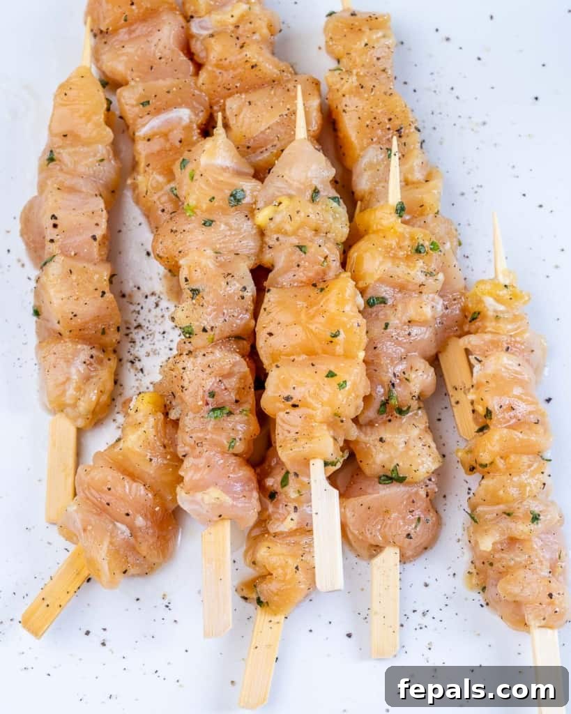 chicken on kabobs with herbs and seasoning, ready for grilling