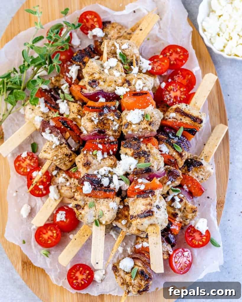top view chicken kabobs garnished with feta cheese, herbs, and tomatoes