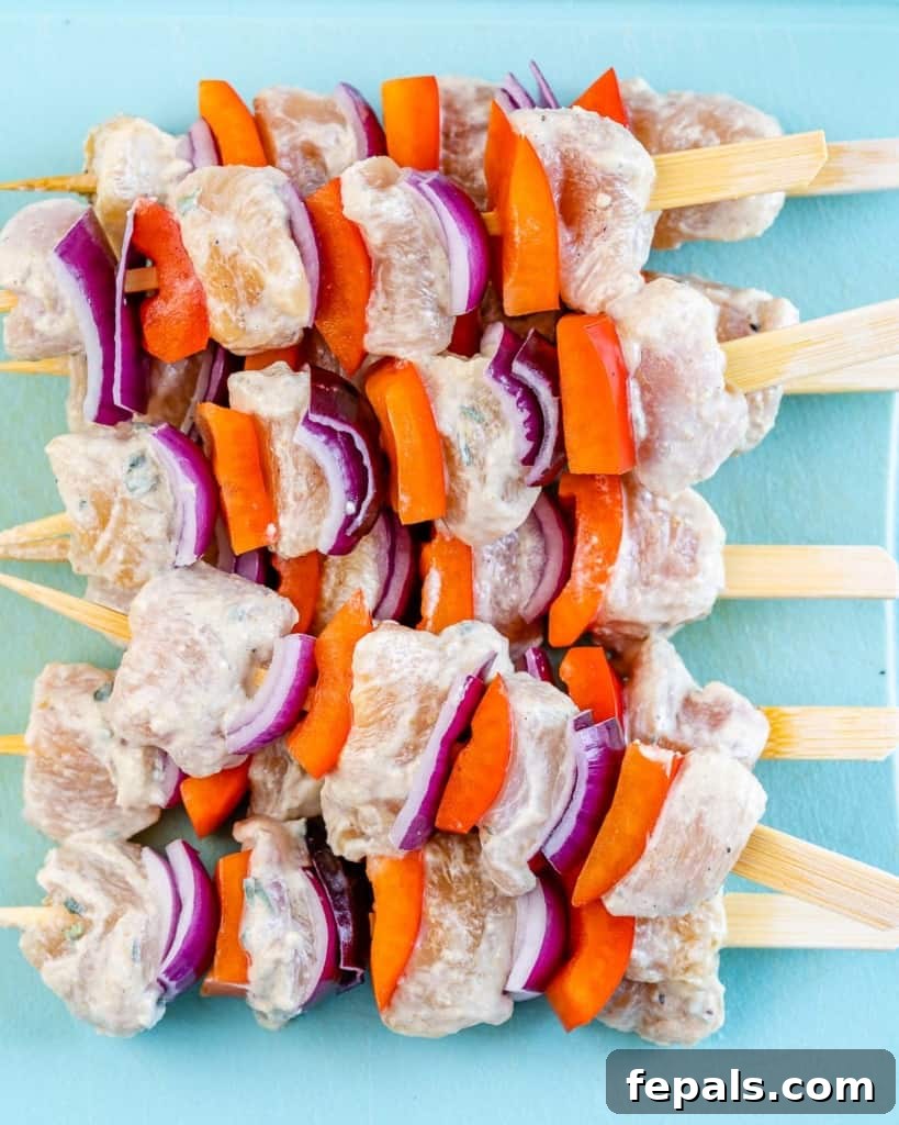raw chicken added to the skewers with bell peppers and onions