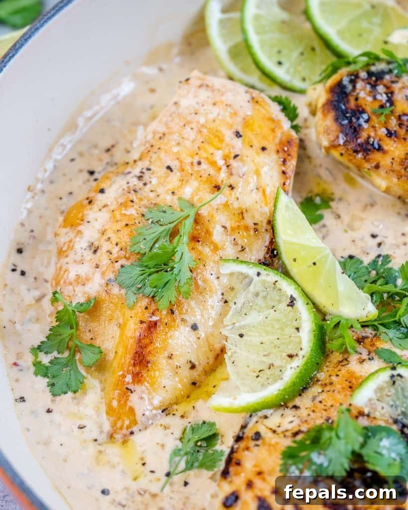 Smoky Chipotle Chicken Skillet 9 A chicken breast in a skillet covered in creamy chipotle sauce, adorned with fresh cilantro and a sliced lime.