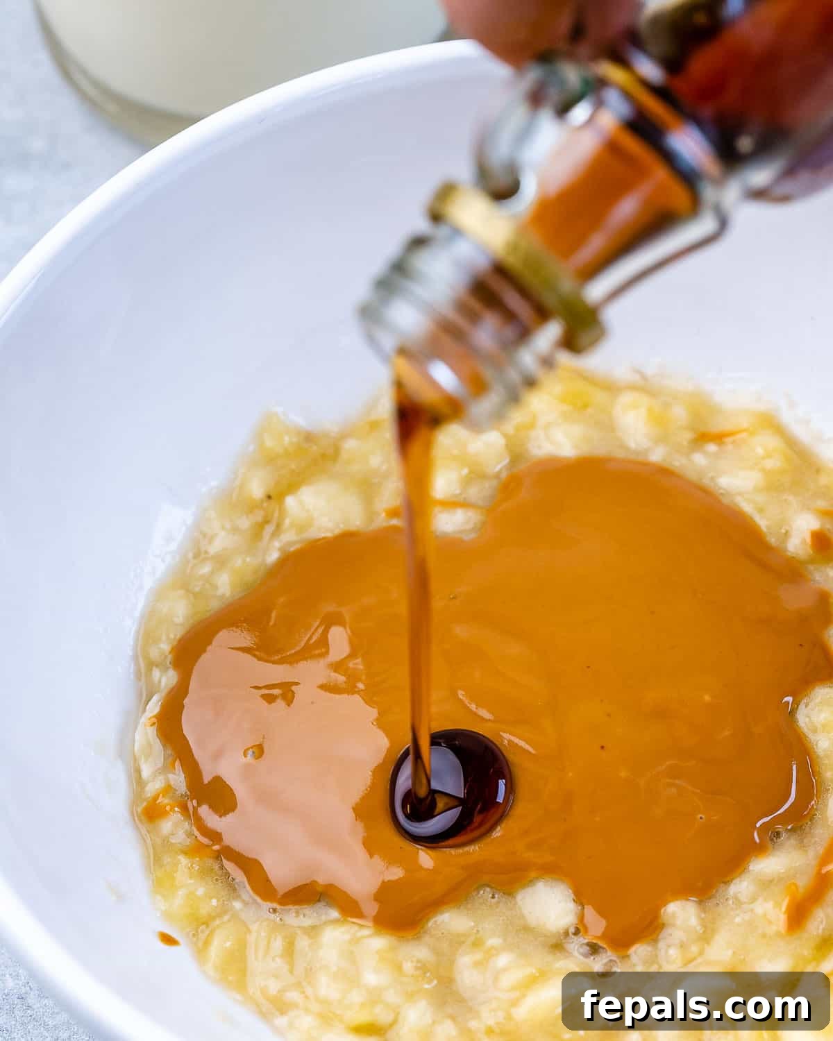 Mashed banana, creamy peanut butter, maple syrup, and vanilla extract combined in a mixing bowl.