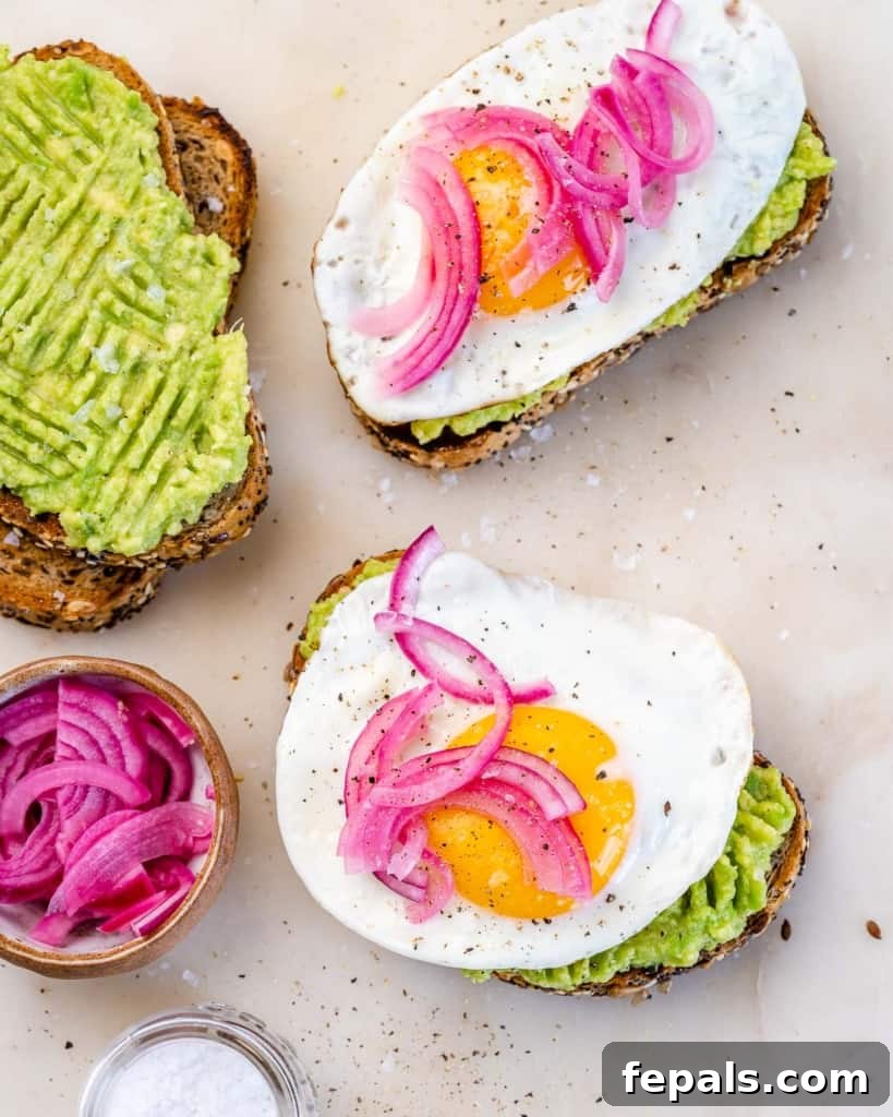 top view avocado toast topped with fried eggs and pickled onions