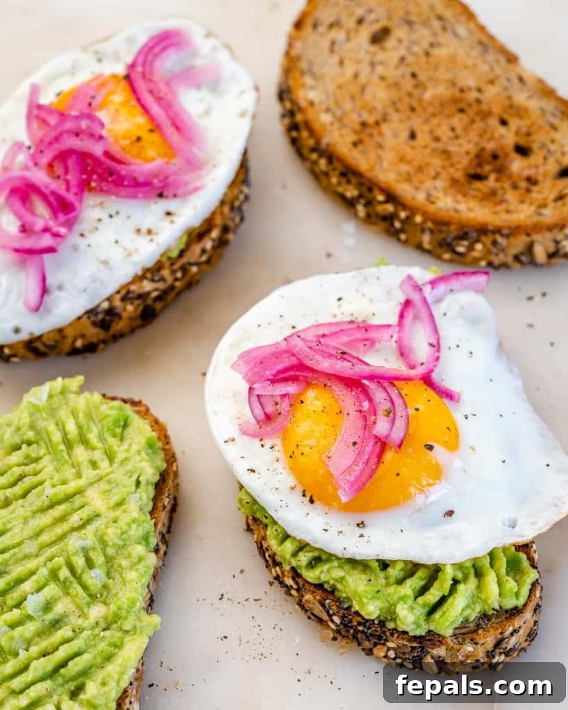 side shot of 4 toast, two topped with eggs, one with just mashed avocado and one just plain toast