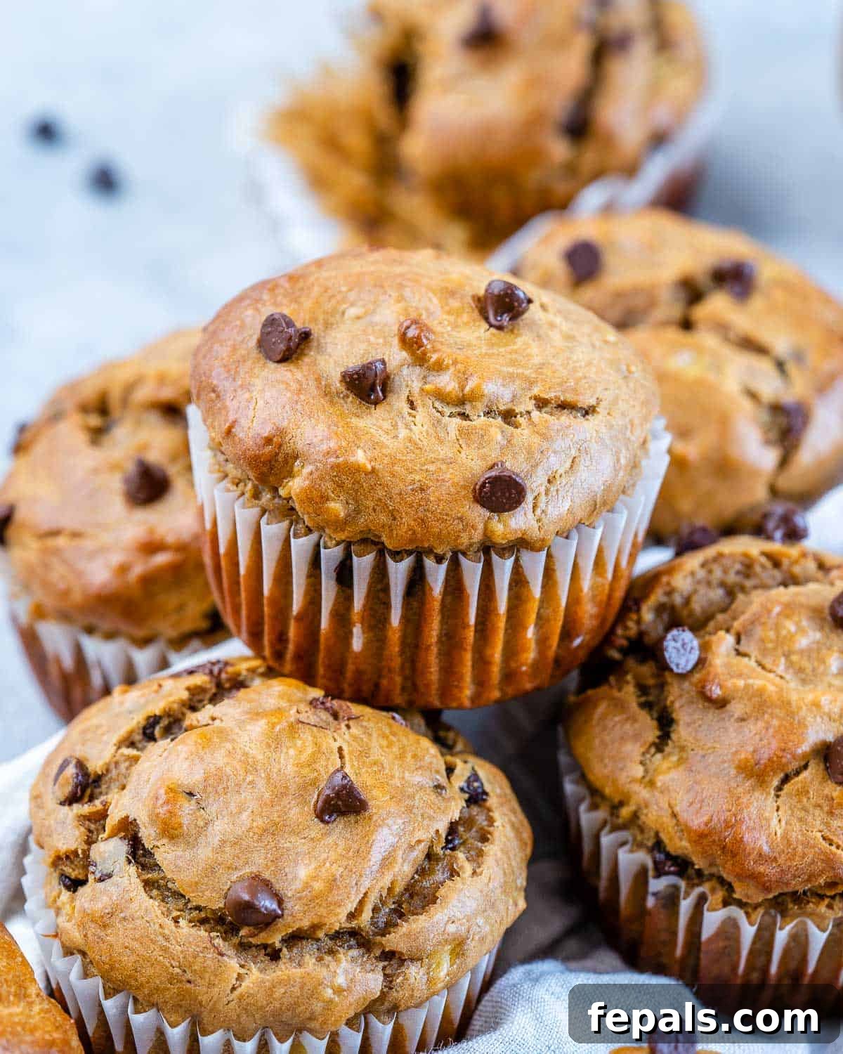 Wholesome Flourless Peanut Butter Banana Muffins 8 A rustic stack of moist, flourless peanut butter banana muffins, showcasing their golden-brown tops and rich texture, on a simple backdrop.
