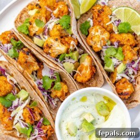 Top-down view of vibrant Parmesan Roasted Cauliflower Tacos with a creamy sauce on the side, ready to be enjoyed.