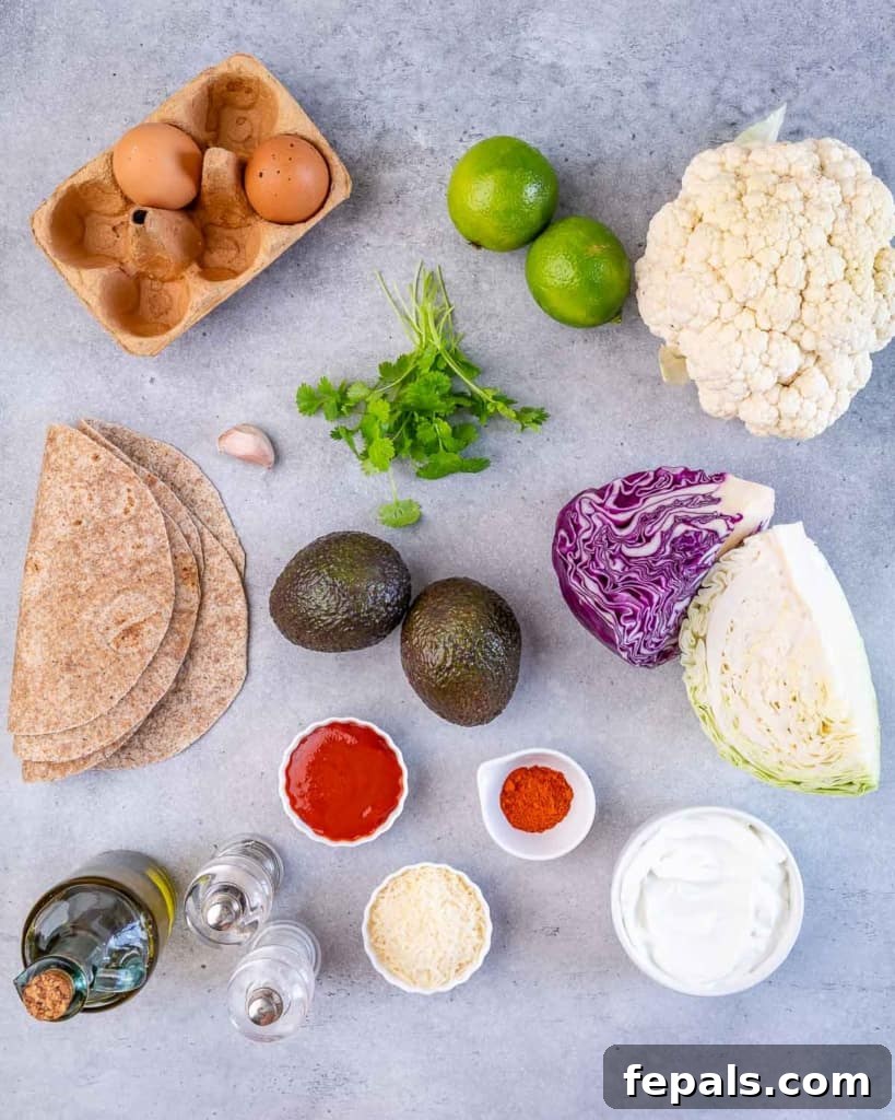 A flat lay of all fresh ingredients required to prepare the vegetarian cauliflower tacos and homemade coleslaw, neatly arranged on a wooden board.