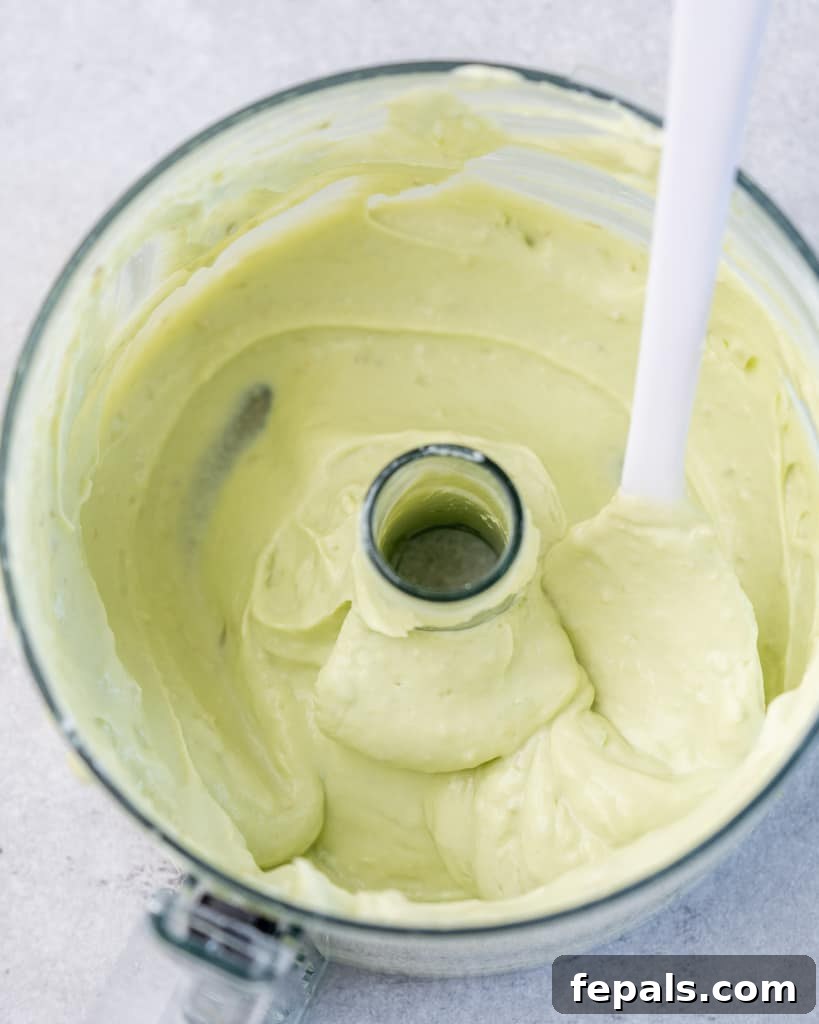 Creamy avocado yogurt sauce being blended to smooth perfection in a food processor, ready for the coleslaw.