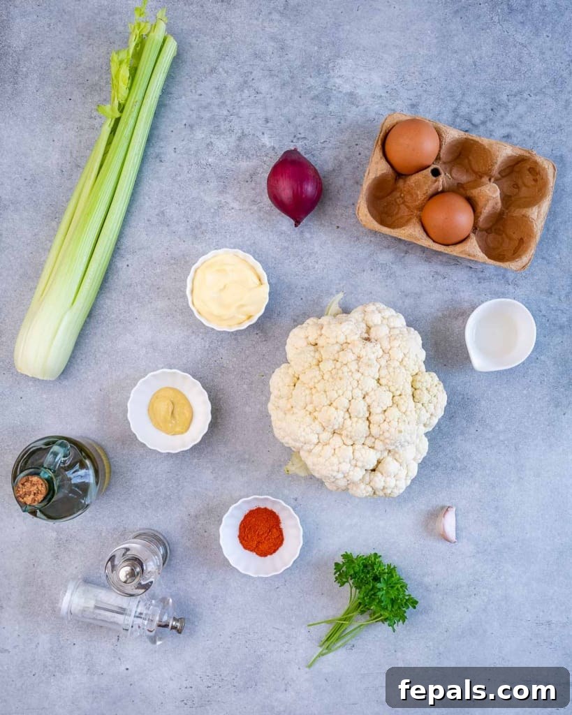 Cauliflower Mock Potato Salad 4 Overhead shot of individual ingredients laid out for keto cauliflower potato salad, including cauliflower, eggs, celery, and dressing components.