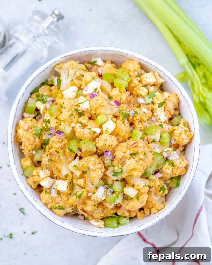Cauliflower Mock Potato Salad 9 Top-down view of a large white bowl filled with keto cauliflower potato salad, garnished with herbs.