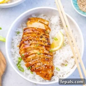 Top view of perfectly sliced baked teriyaki chicken breast over a bowl of rice.