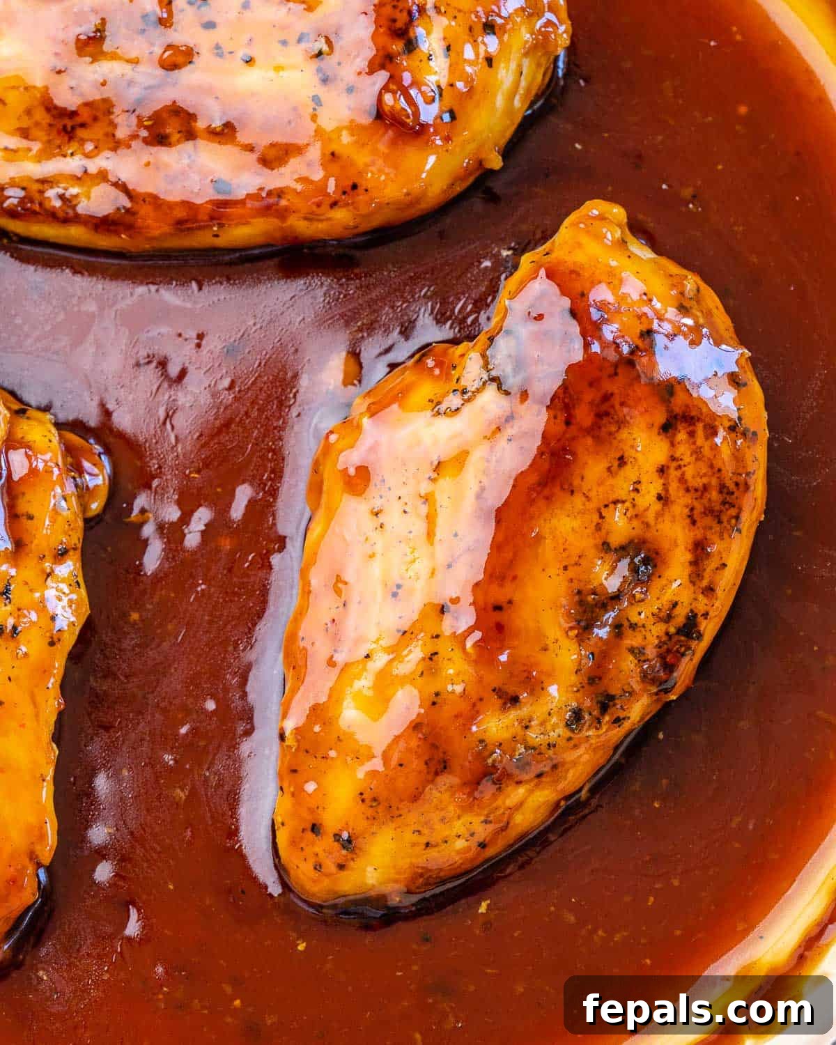 Vibrant homemade teriyaki sauce being poured over seared chicken breasts in a hot skillet, creating a rich, glossy coating.