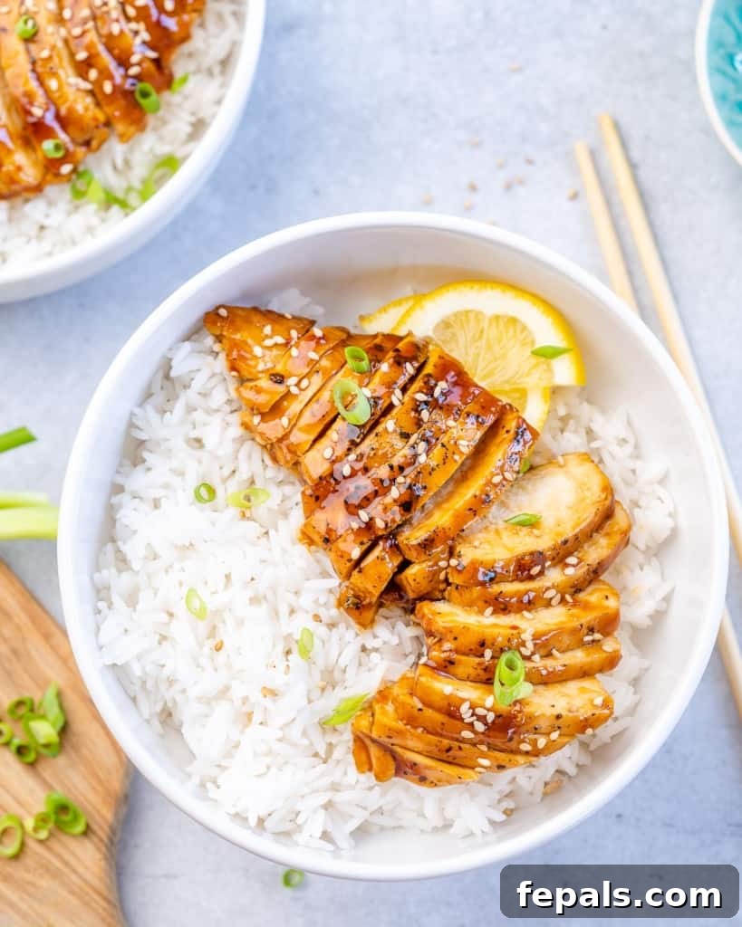 Top shot of the succulent chicken teriyaki served with white rice in a pristine white bowl, garnished with fresh green onions.