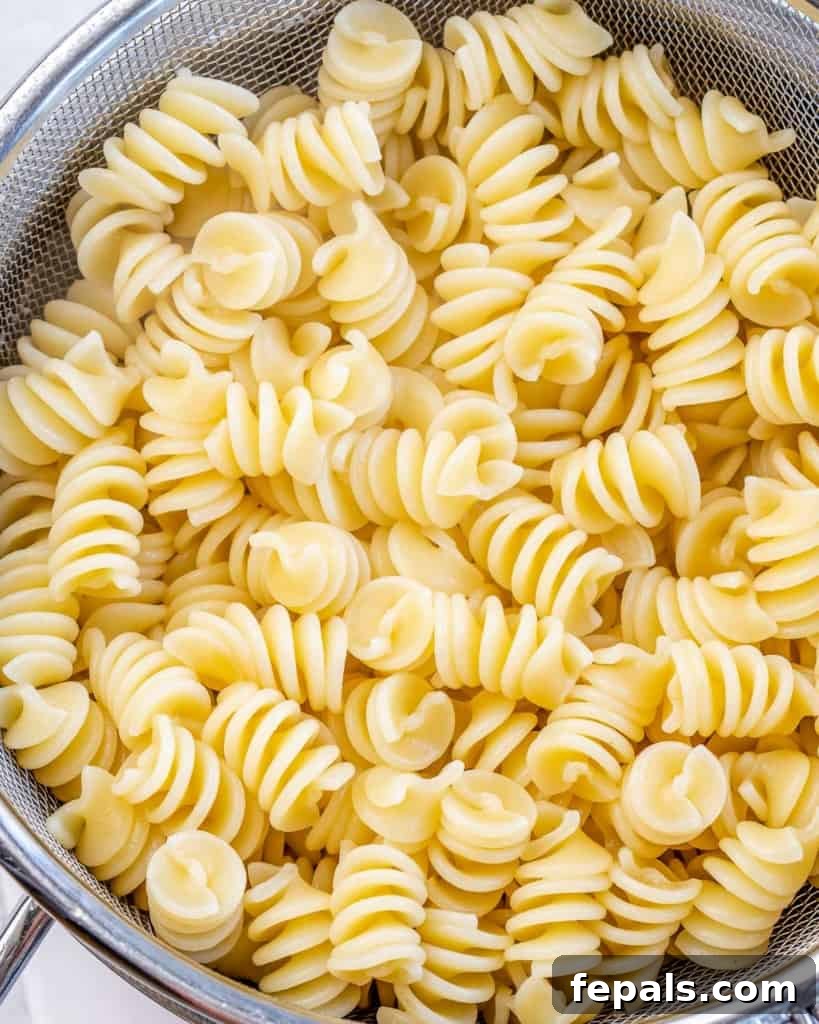 A colander filled with perfectly cooked pasta, freshly drained and ready to be tossed with the savory Cajun cream sauce.
