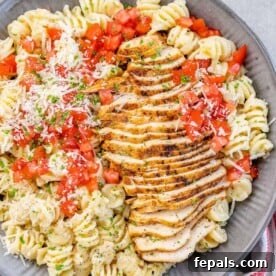 Top view of a pasta bowl with sliced Cajun chicken breast, garnished with tomatoes and Parmesan, representing the final dish.