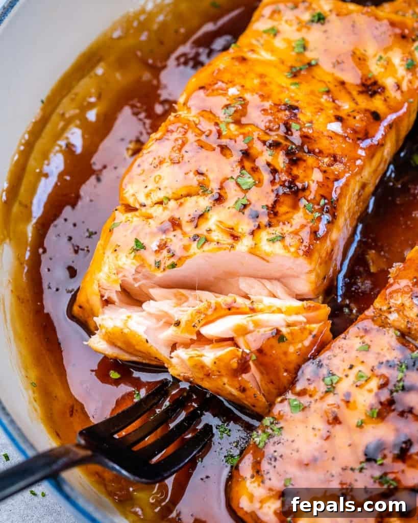 Close-up of a flaked salmon fillet, glistening with honey garlic sauce, ready to be enjoyed.
