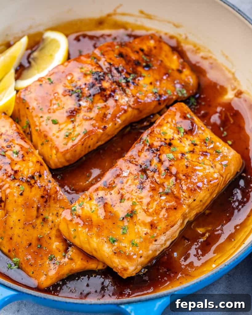 Side shot of three honey glazed salmon fillets beautifully presented in a pan.