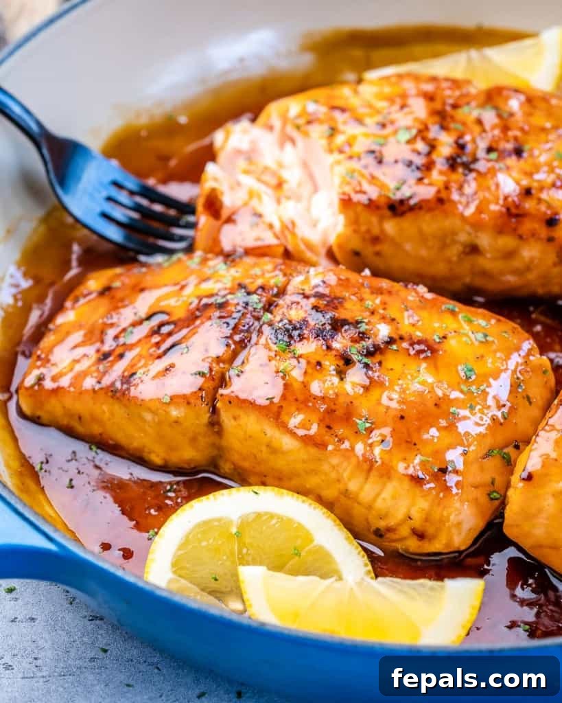 Side shot of glazed salmon fillets in a vibrant blue skillet, ready to serve.