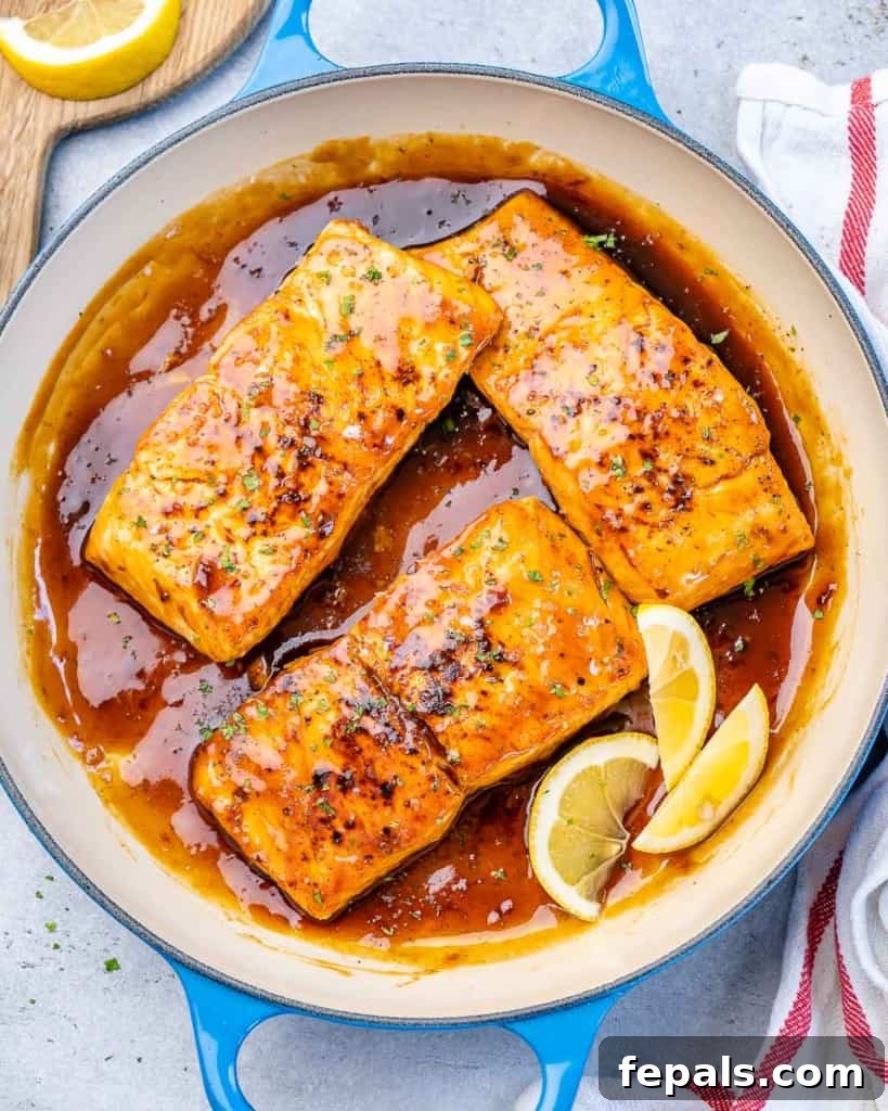 Top view of three perfectly glazed salmon fillets in a pan with a rich honey garlic sauce.