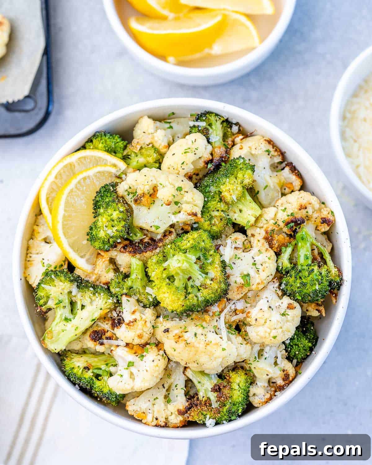 top view of cauliflower and broccoli in bowl with lemon and parsley, ready to be roasted