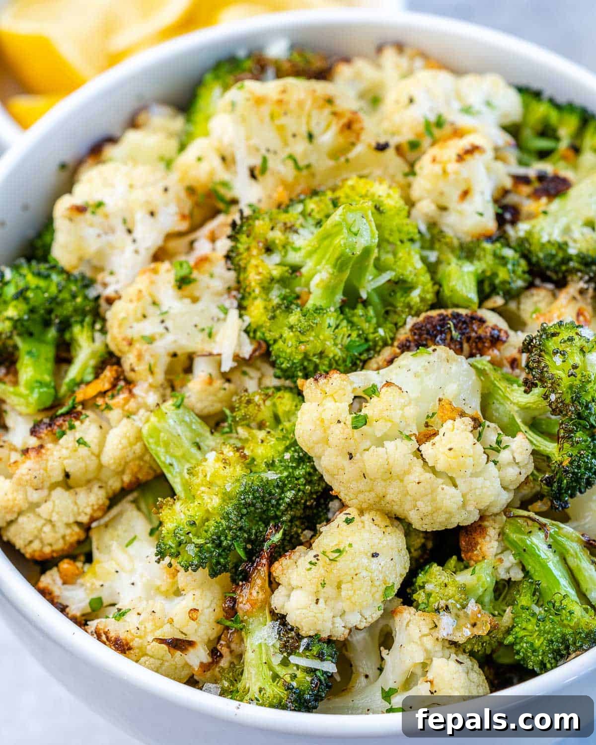 front view of roasted cauliflower and broccoli in white bowl, perfectly golden and tender
