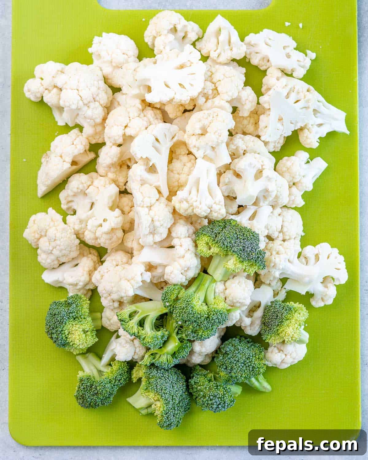 florets of cauliflower and broccoli on green cutting board, showing preparation