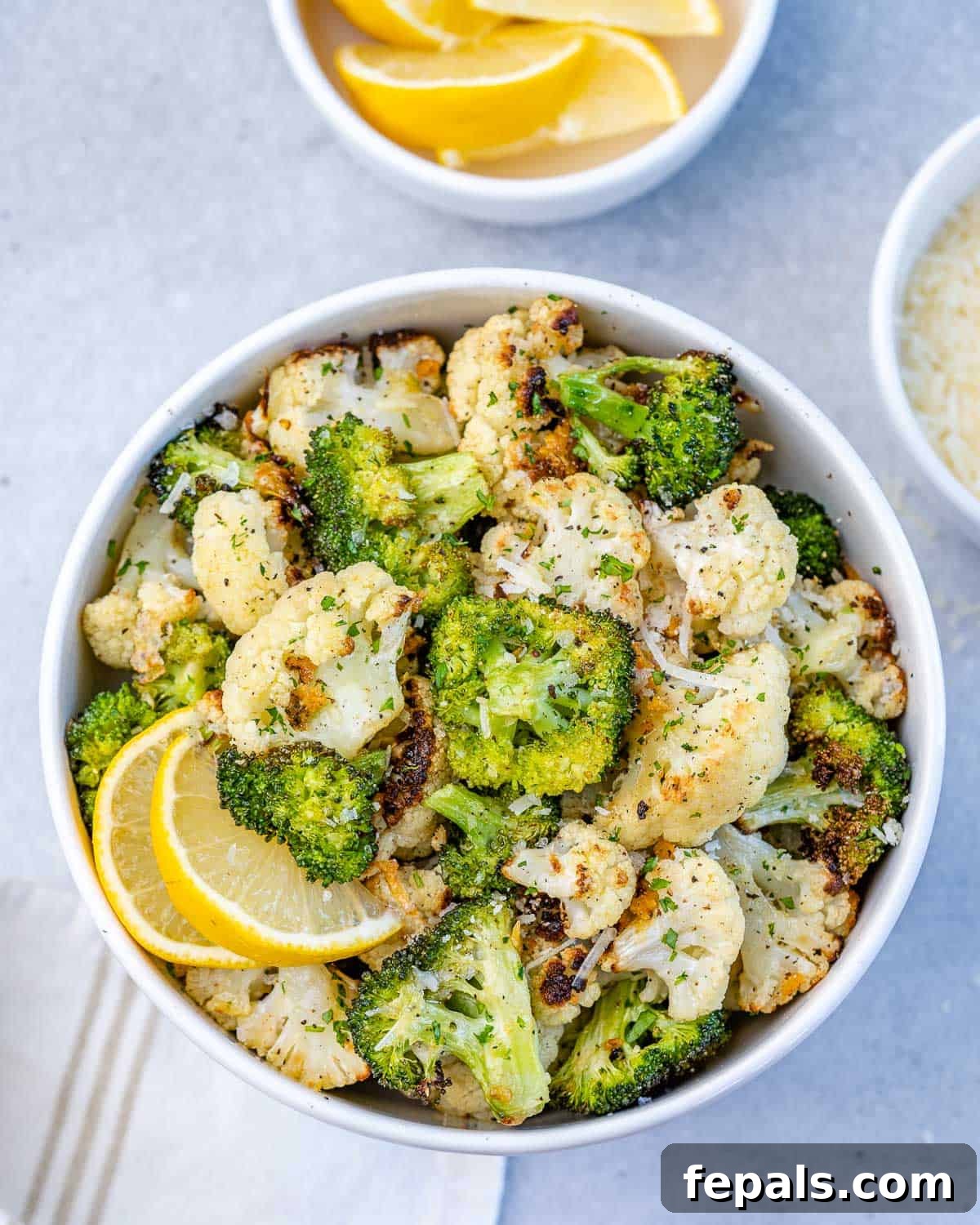one bowl of roasted broccoli and cauliflower with lemon slices, ready to be served