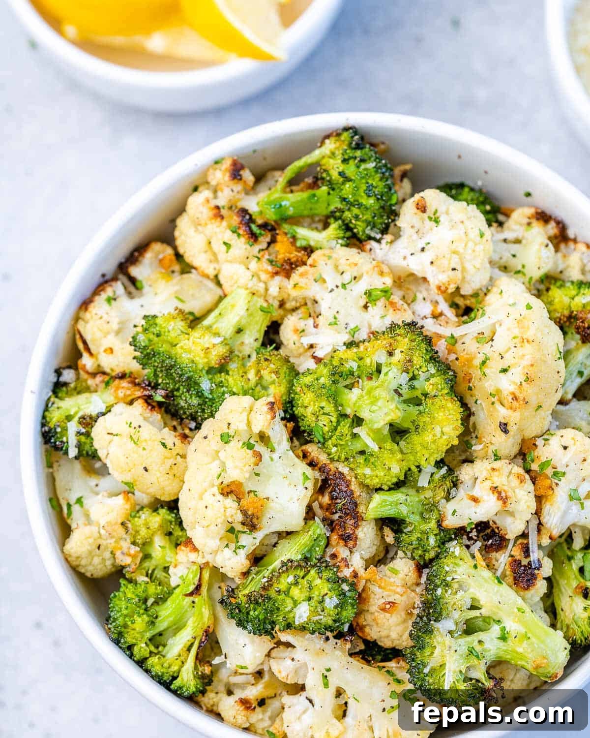 bowl of roasted cauliflower and broccoli with lemon and garlic, perfectly seasoned