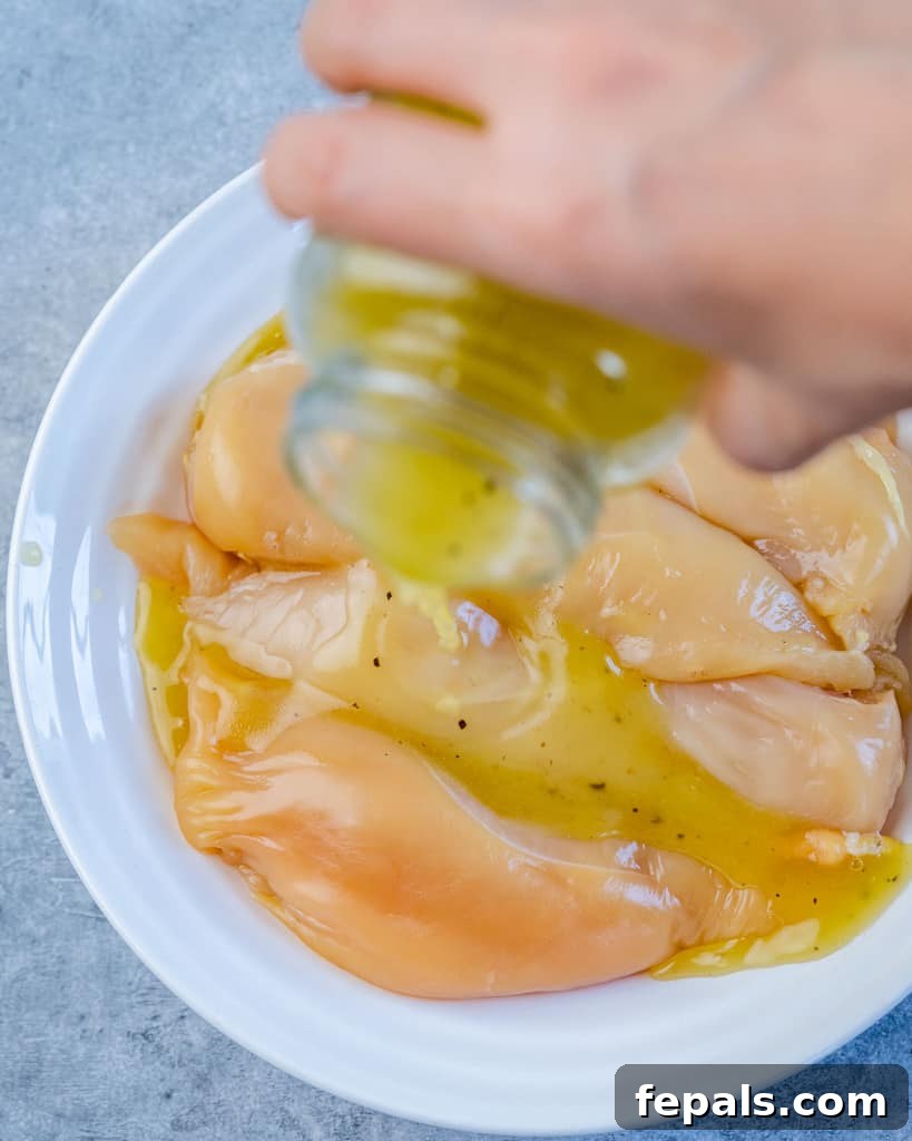 honey lemon marinade being poured over raw chicken breasts in a bowl, ready for marinating