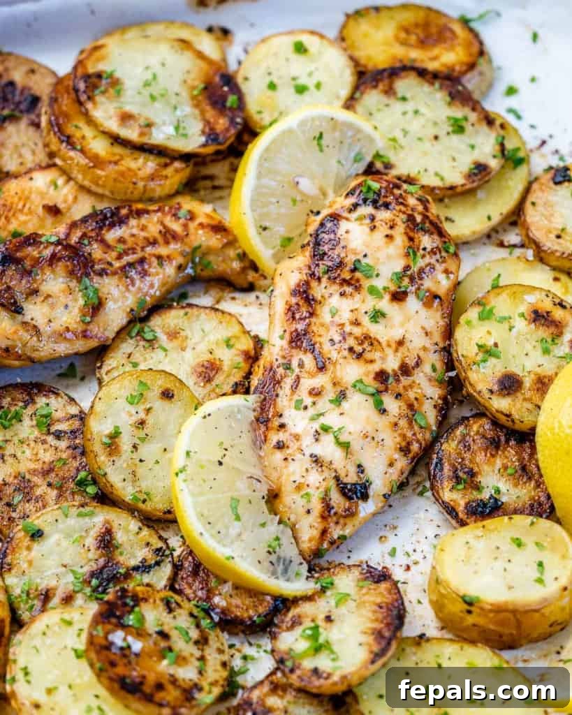 close up side shot of baked honey lemon chicken breast with golden roasted potatoes, highlighting the texture and glaze