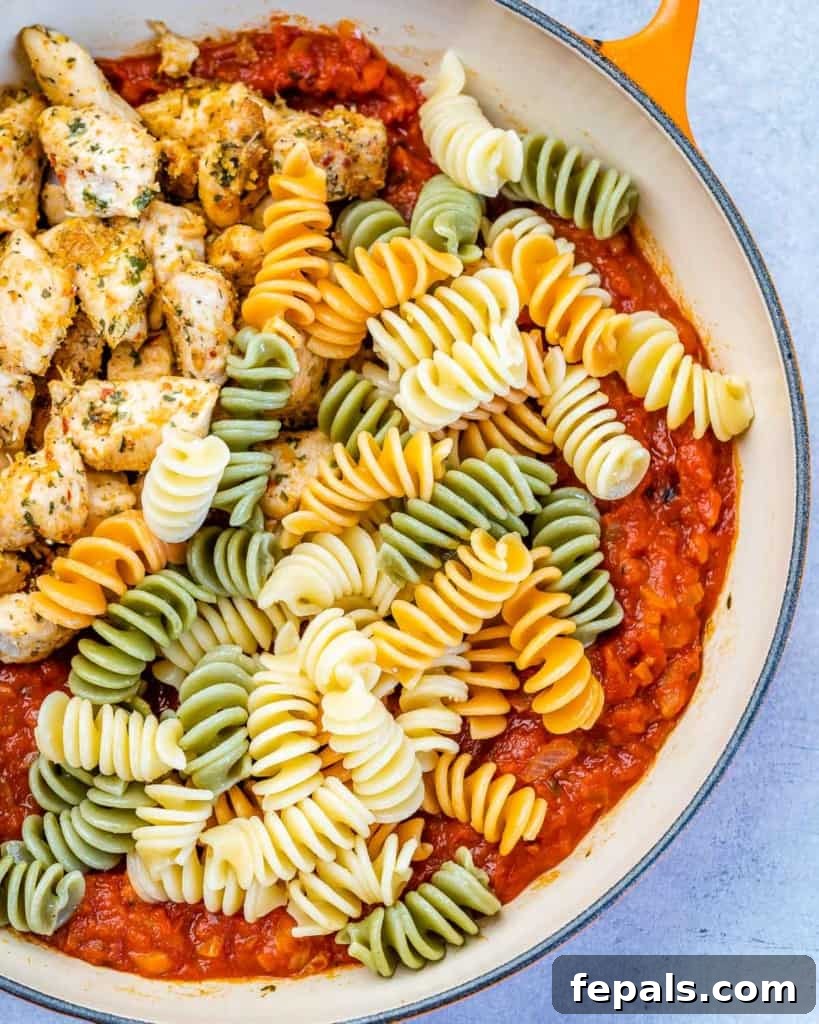 Comforting Chicken Parmesan Pasta 6 cooked pasta poured in with chicken bites and marinara sauce in the skillet.