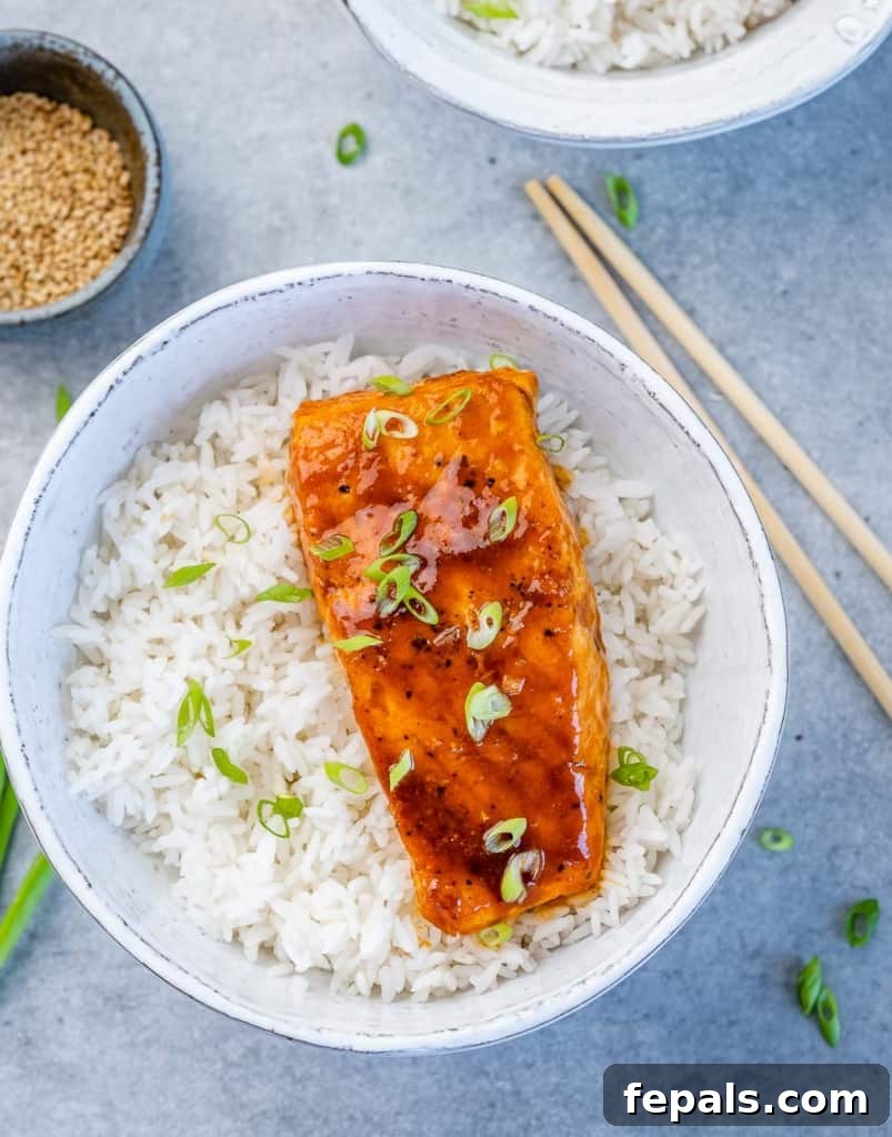 Sweet and Sticky Pan Seared Salmon 3 top view salmon filet over a bowl of rice garnished with green onions with chop sticks on the side