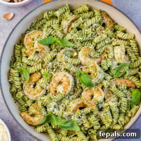 top view of pesto pasta with shrimp in an orange skillet