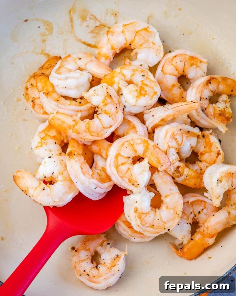 cooked shrimp in a pan with red spatula in it 
