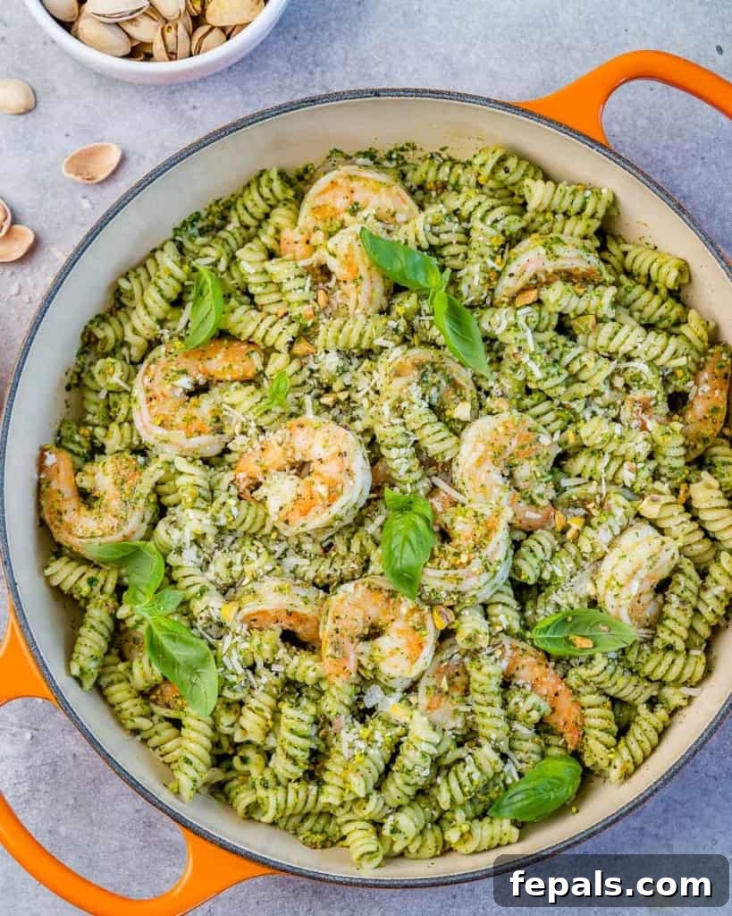 top view of pesto pasta in an orange skillet with shrimp