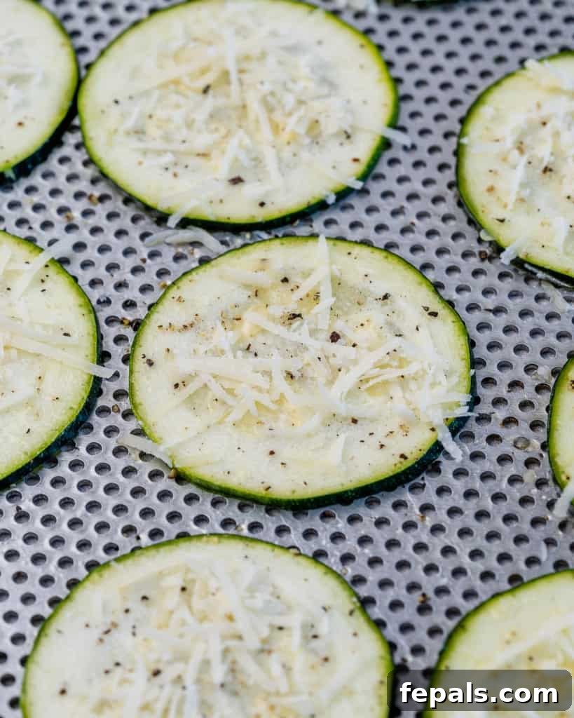 Crispy Air Fryer Zucchini Bites 6 zucchini laid flat with parmesan cheese and black pepper sprinkled over it.