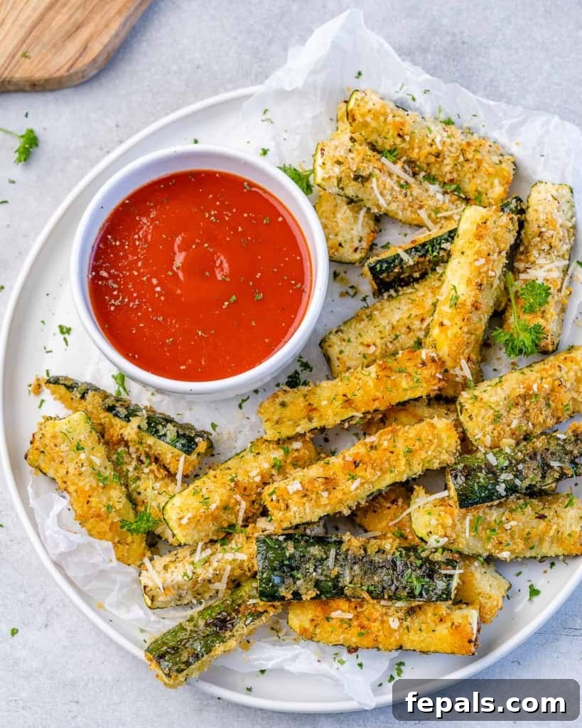 Crispy Air Fryer Zucchini Parmesan Fries 2 top view zucchini fries on a white plate with a side of ketchup